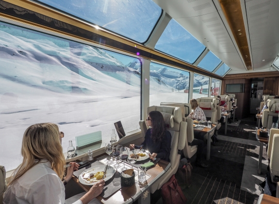 Train travellers look out of the window and the snowy Alpine scenery