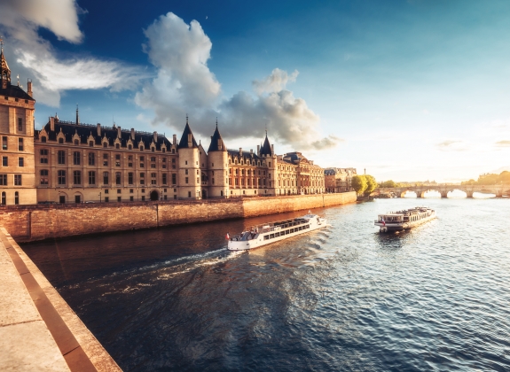 Dramatic sunset over river Seine and Conciergerie in Paris, France, with cruise boats and Pont Neuf. Colourful travel background. Romantic cityscape.