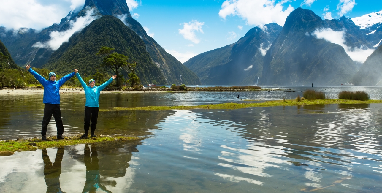 Happy couple on the beach near the waterfall, the fjords of New Zealand.