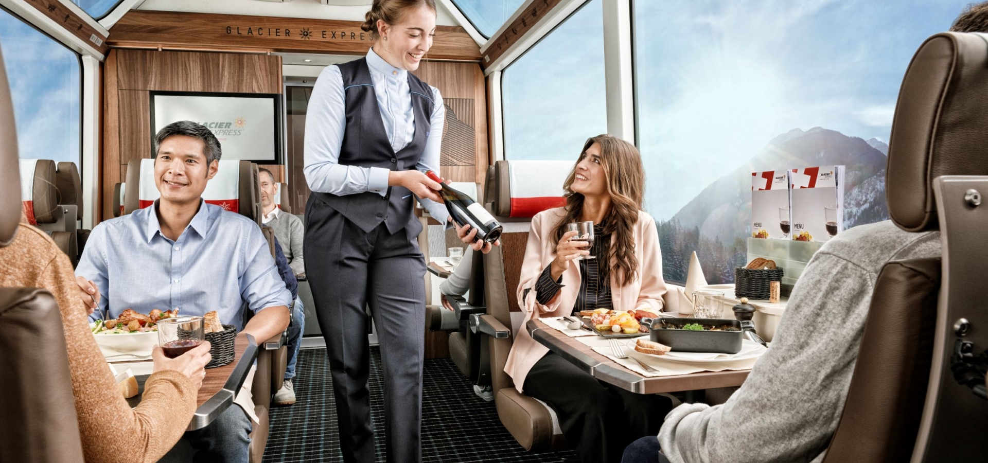 Train staff serve onboard customers with drinks in luxurious carriage