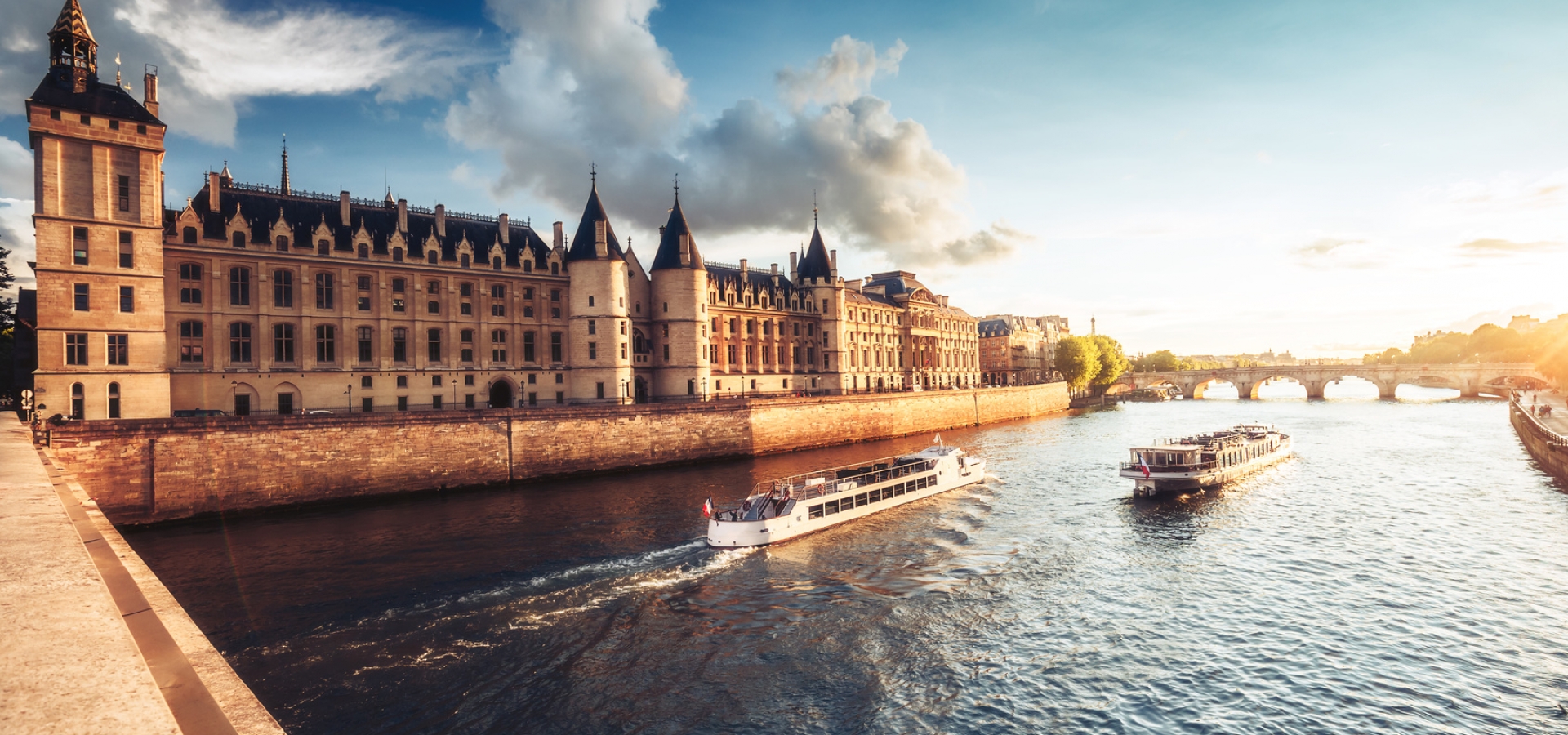Dramatic sunset over river Seine and Conciergerie in Paris, France, with cruise boats and Pont Neuf. Colourful travel background. Romantic cityscape.