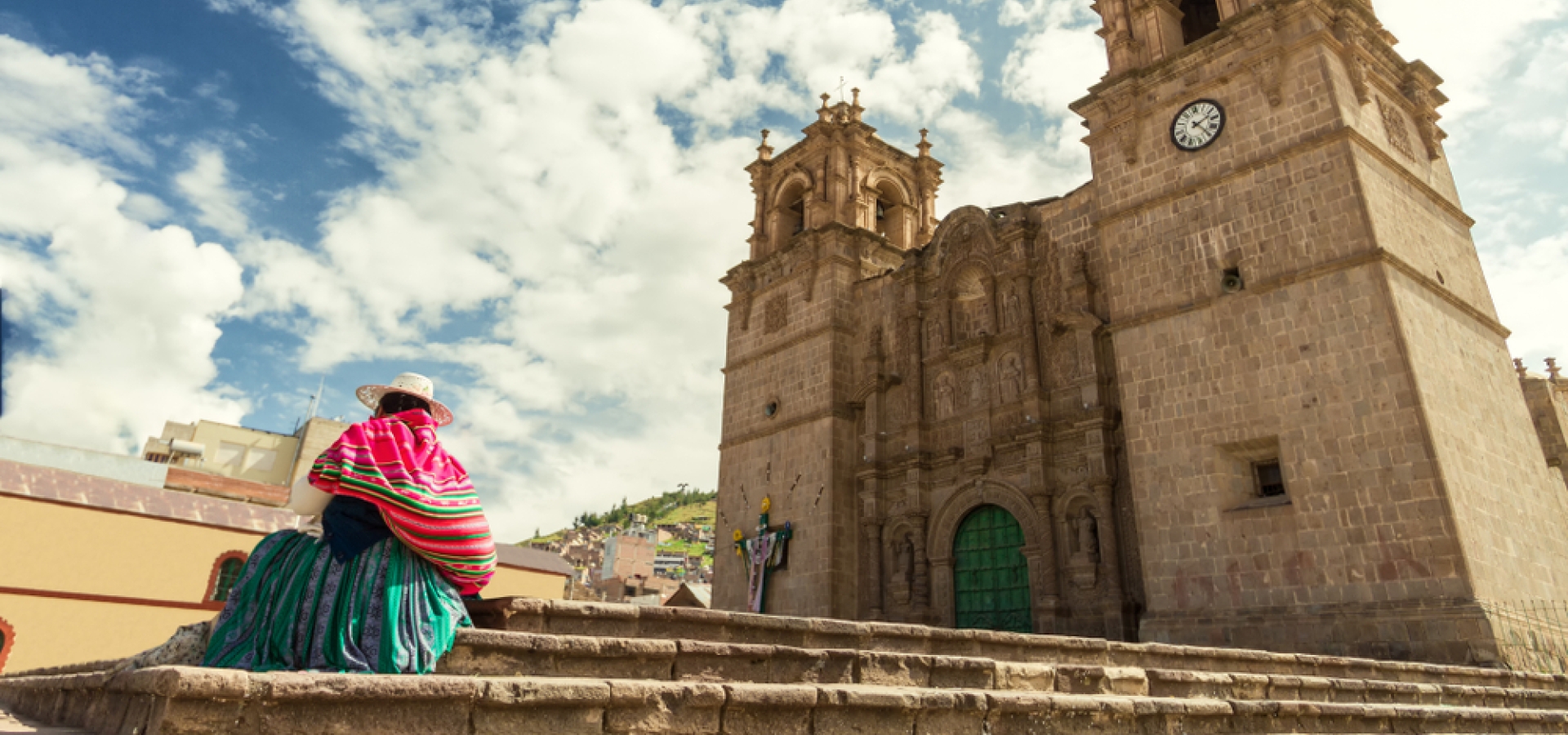 Woman with keperina (bag on her back) sitting on the steps of the Cathedral of Puno (Peru)