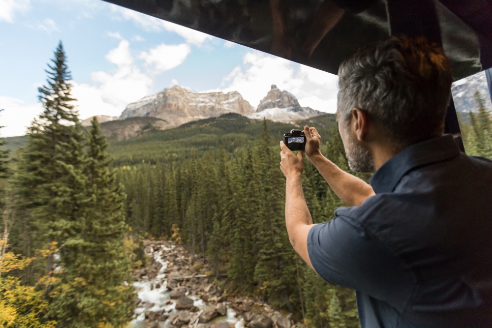 man taking picture of mountains from Rocky Mountaineer platform